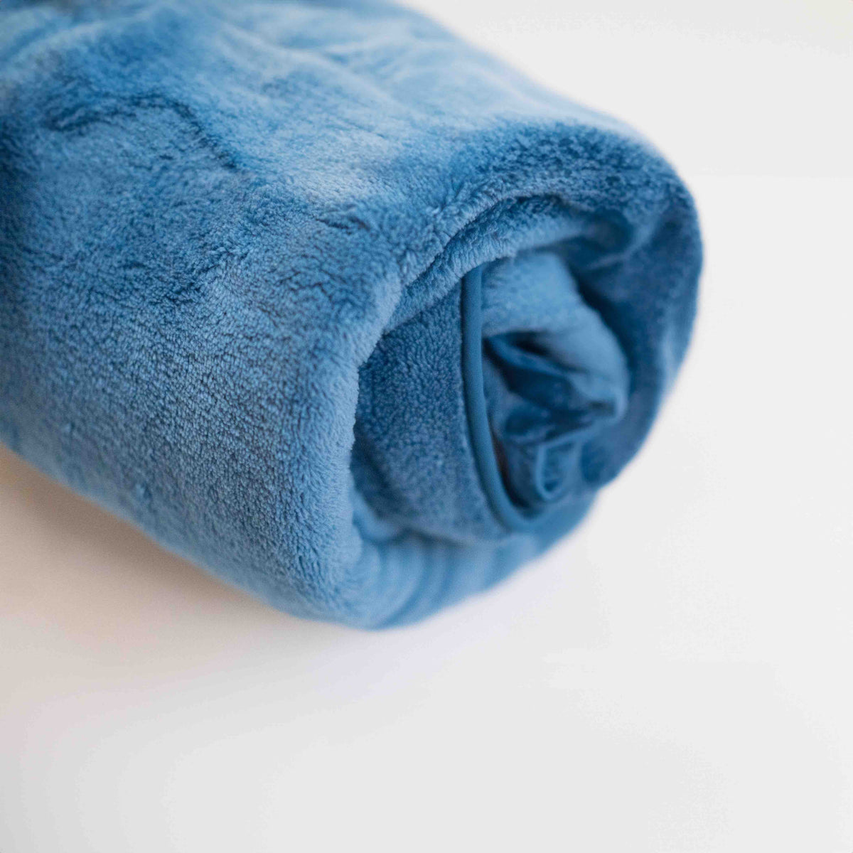 El Ocean Breeze Dog Towel Robe azul, enrollado en un bulto compacto.